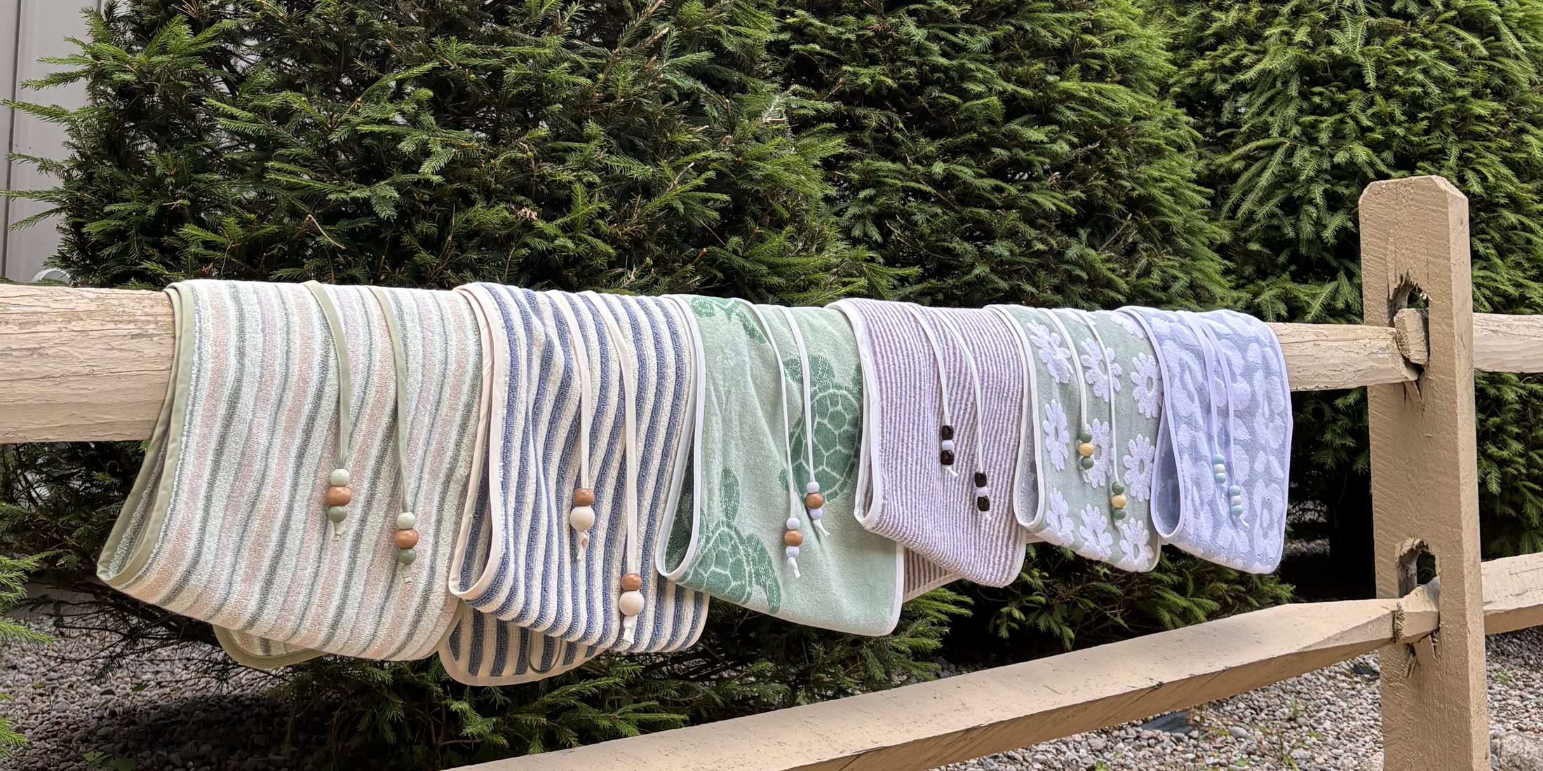 Hand-sewn towel wrap skirts in stripes, sea turtles and daisies hanging on a fence rail